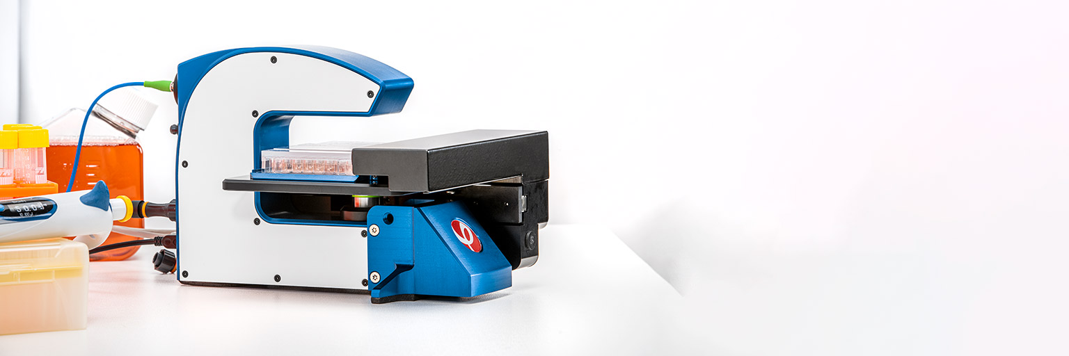 A HoloMonitor microscope placed on a white lab bench with cell lab tools.